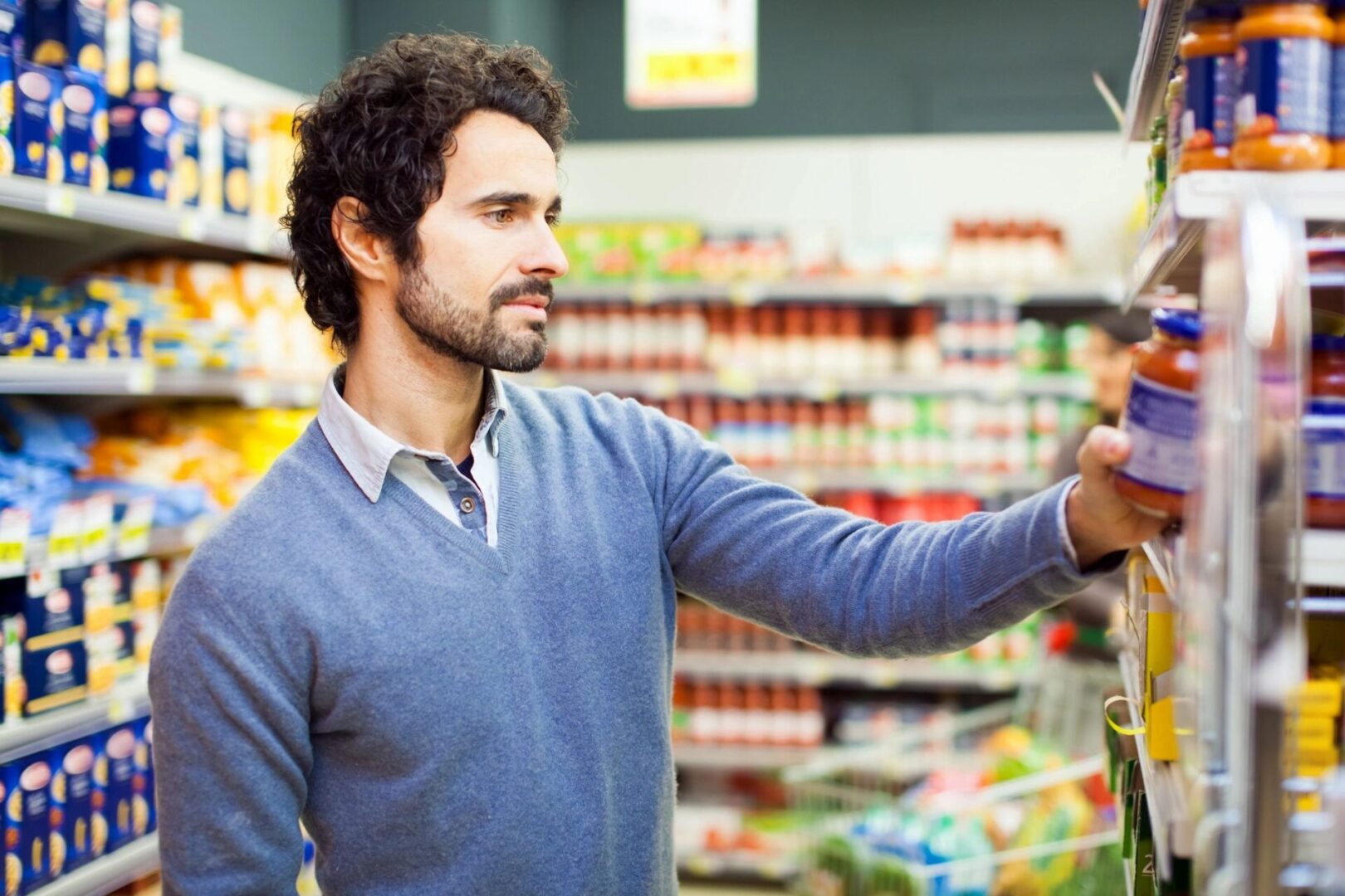 A man in a grocery store holding a knife.